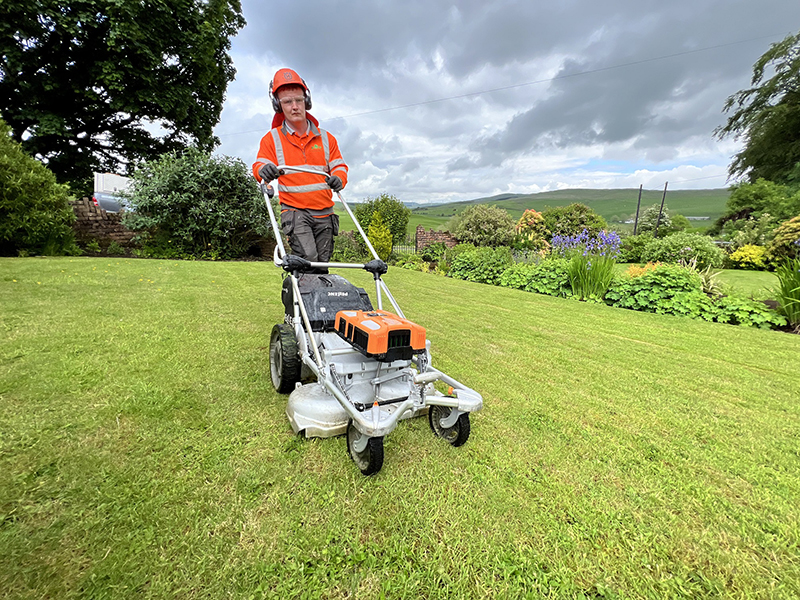 Image of worker cutting grass using electric mower